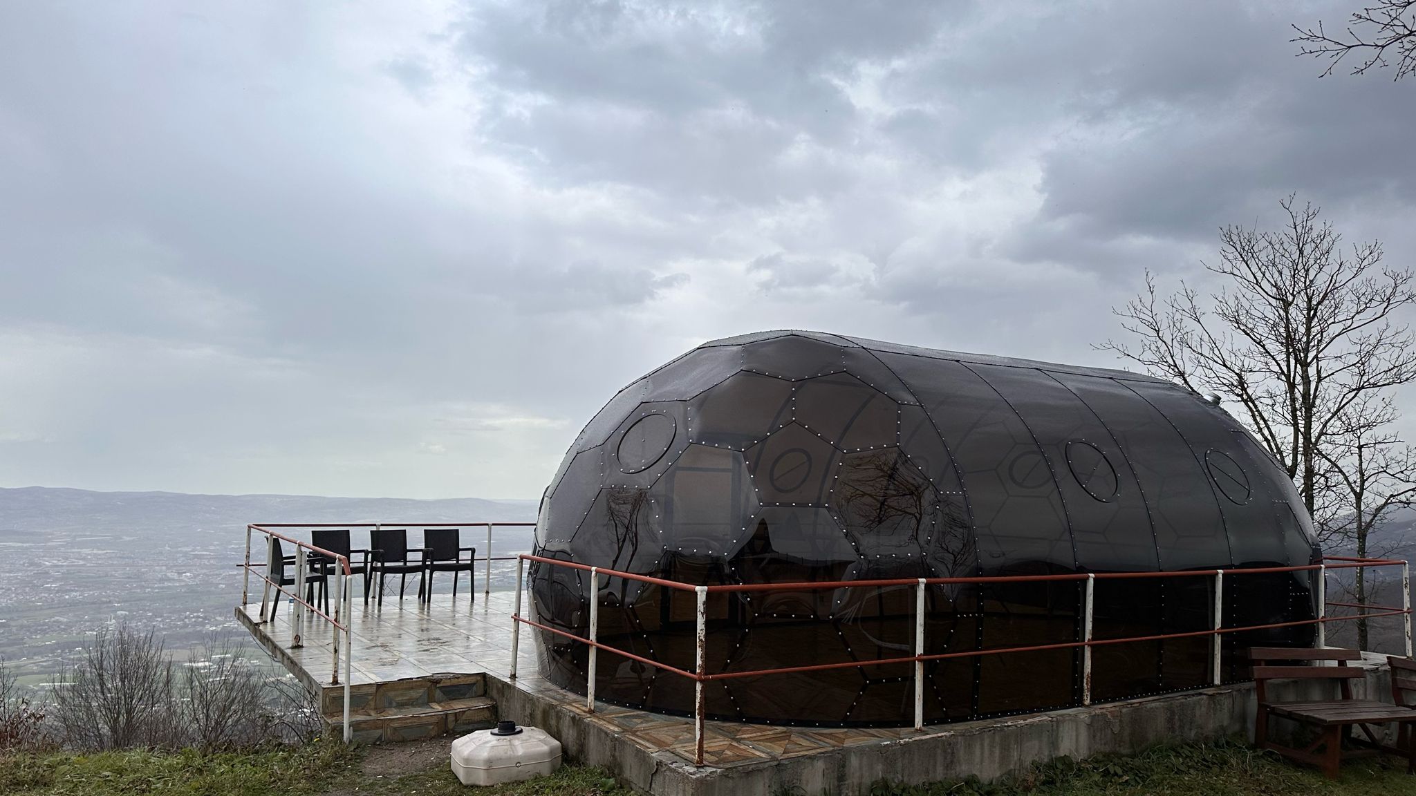 Dunkel getönter Kuppelpavillon mit runden Fensterelementen auf einer Aussichtsterrasse